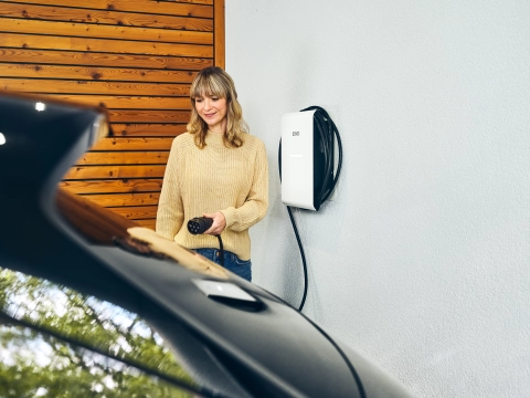 Junge Frau lädt ihr Elektroauto in der Garage zuhause.